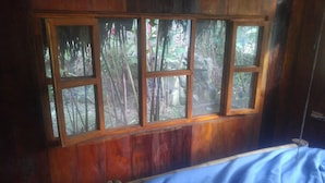 A wooden-framed window with multiple panes, revealing a view of bamboo and foliage outside. - Finca De Buen Consejo - Hostel (Pacto)