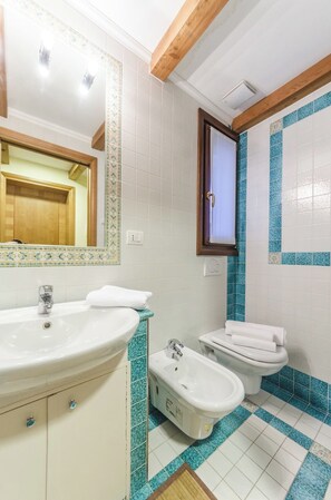 Une salle de bain équipée d’un lavabo, d’un bidet, de toilettes et d’un miroir avec un cadre en bois.