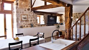 A rustic kitchen with a wooden island, stone walls, and a wooden staircase. - Les Picardies (Lesterps)