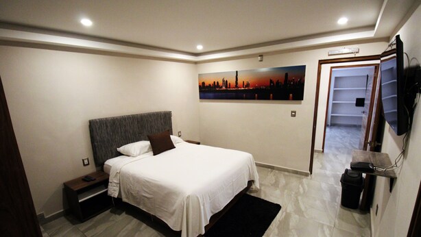 A bedroom with a bed, nightstand, and a painting on the wall. - Oslo 10 (Mexico City)
