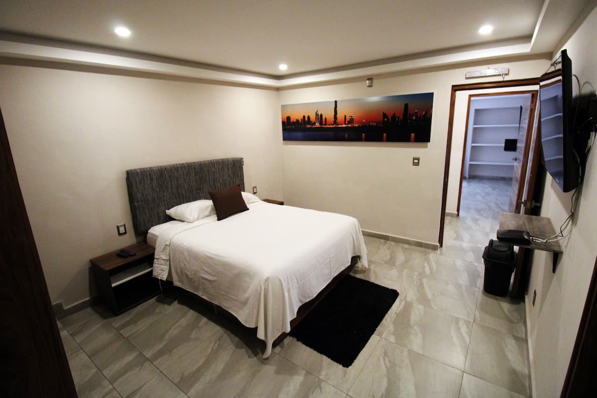 Une chambre à coucher avec un lit, une table de chevet et un tableau accroché au mur.