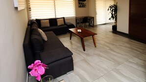 A modern living room with a dark-colored sofa, a wooden coffee table, and a potted orchid. - Oslo 10 (Mexico City)