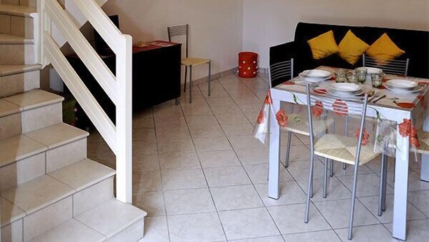 A modern interior with a staircase, dining area, and artwork. - Confort (Comacchio)