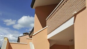 A residential building with a staircase leading to a door, a window, and a light fixture. - Confort (Comacchio)