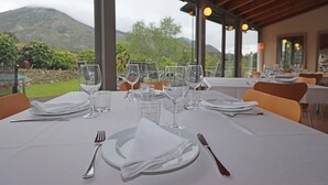 Mesa de comedor para cuatro personas con vista a la montaña, ventanas grandes y techo de madera.