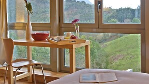 Una habitación con una cama, una mesa de madera con un florero, un tazón y una bandeja con alimentos.
