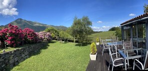 A patio area with outdoor seating, a stone wall, and a view of mountains. - Hotel El Babú (Caravia)