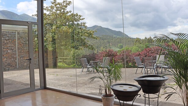 Un patio con mobiliario exterior, un muro de piedra y vistas a montañas.
