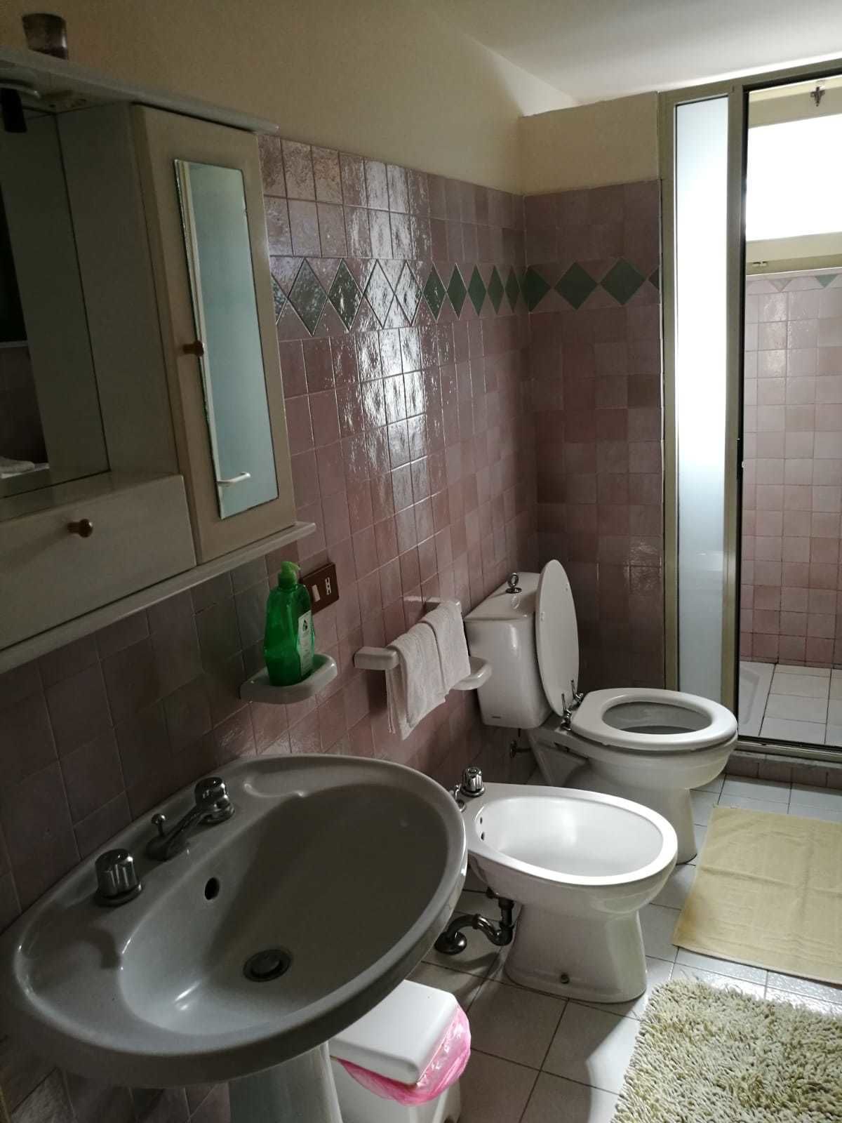 Un baño con dos inodoros, un lavamanos, un espejo y una zona de ducha.