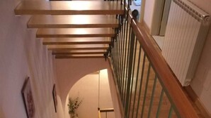 Un escalier en bois avec une rampe en métal, menant à l’étage supérieur.