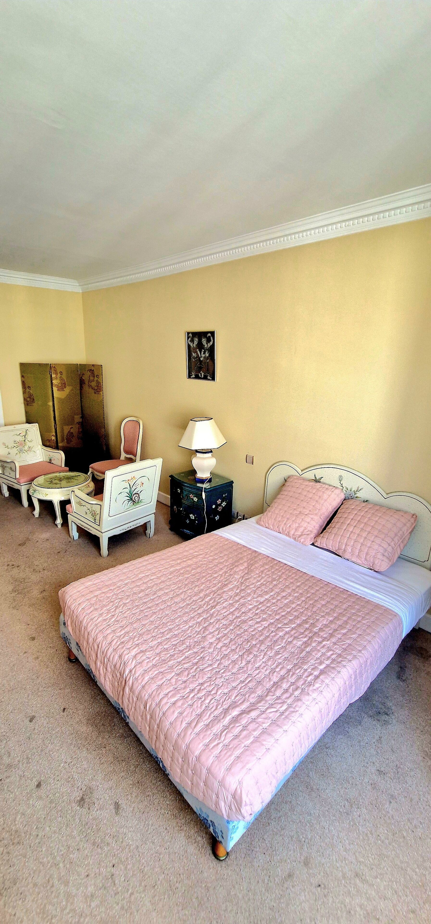 A bedroom with a large bed, a desk, a chair, and a dresser.