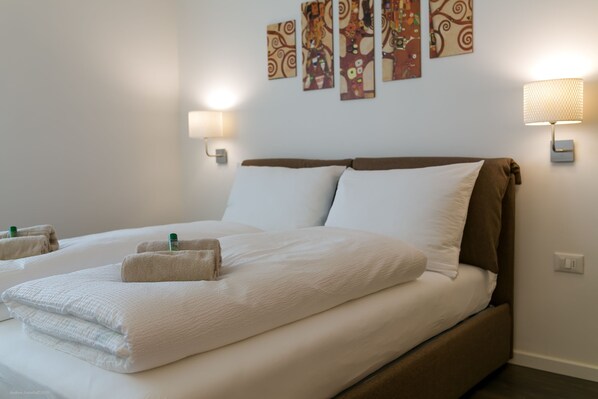 A hotel room with a large bed, two bedside lamps, and artwork on the wall. - Apartment Diamant (Bolzano)