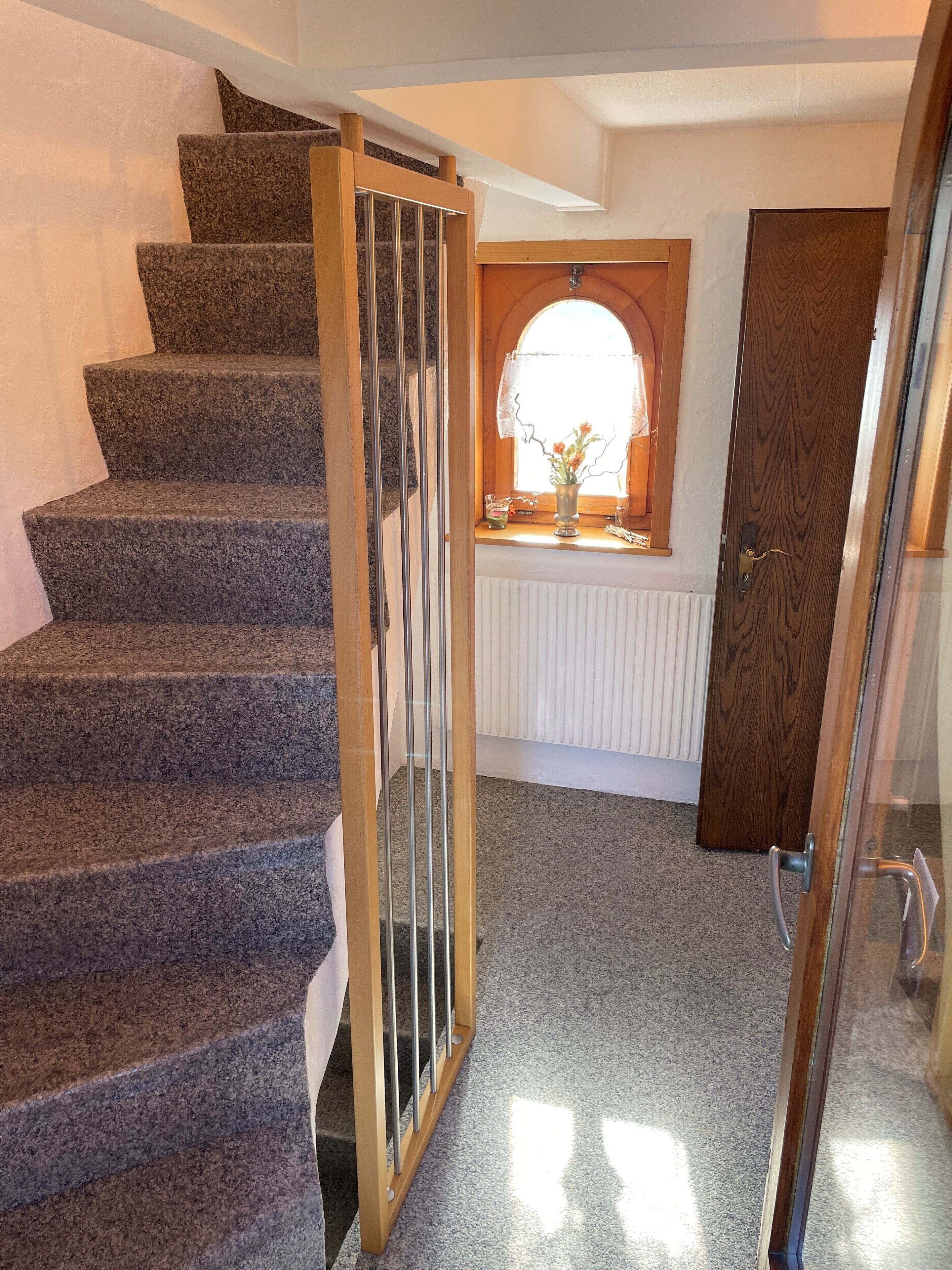A staircase with a glass railing, a wooden door, and a window with a decorative frame.