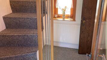 A staircase with a glass railing, a wooden door, and a window with a decorative frame.