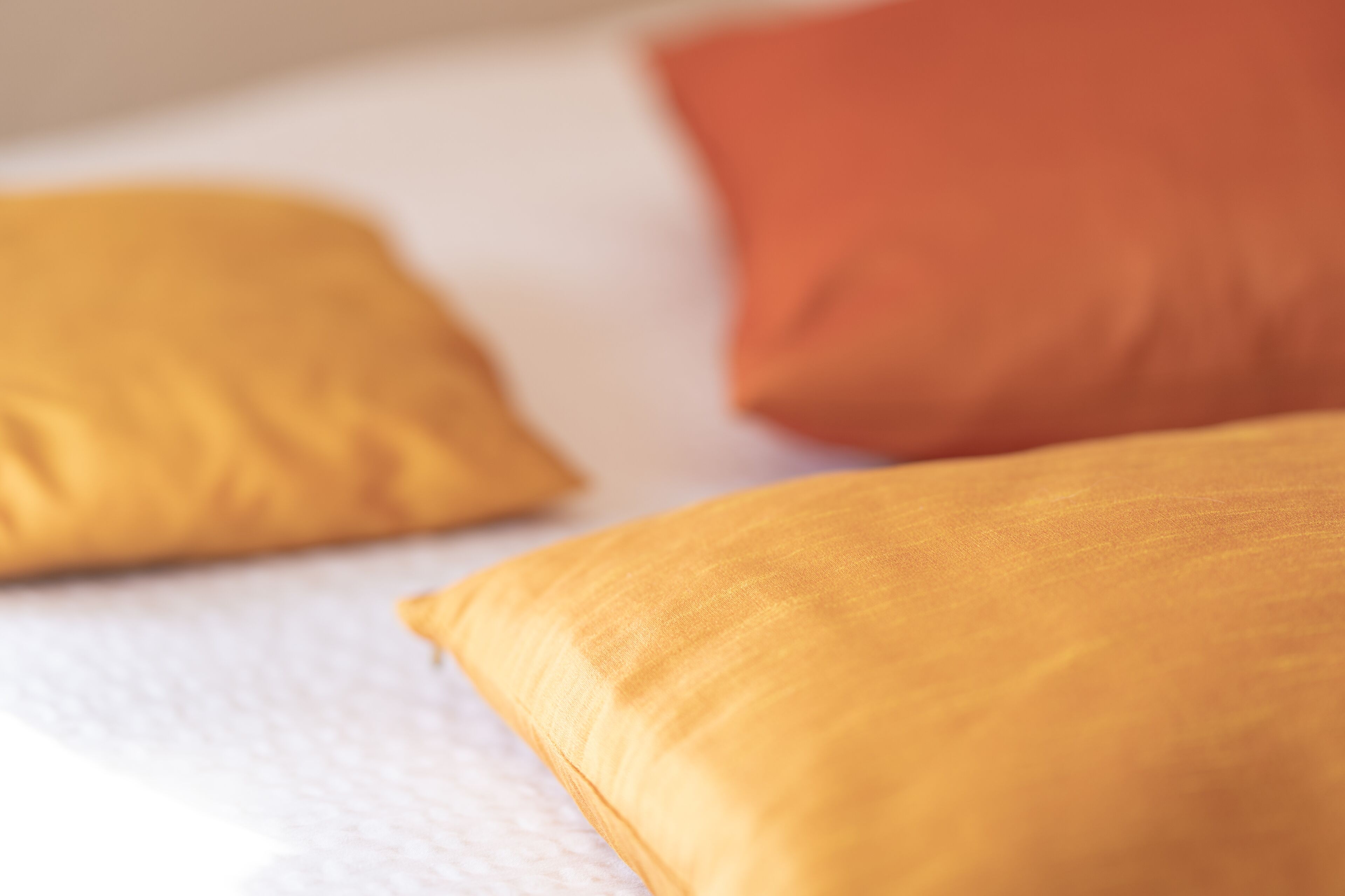 Un gros plan d’un lit avec deux oreillers, un jaune et un orange.