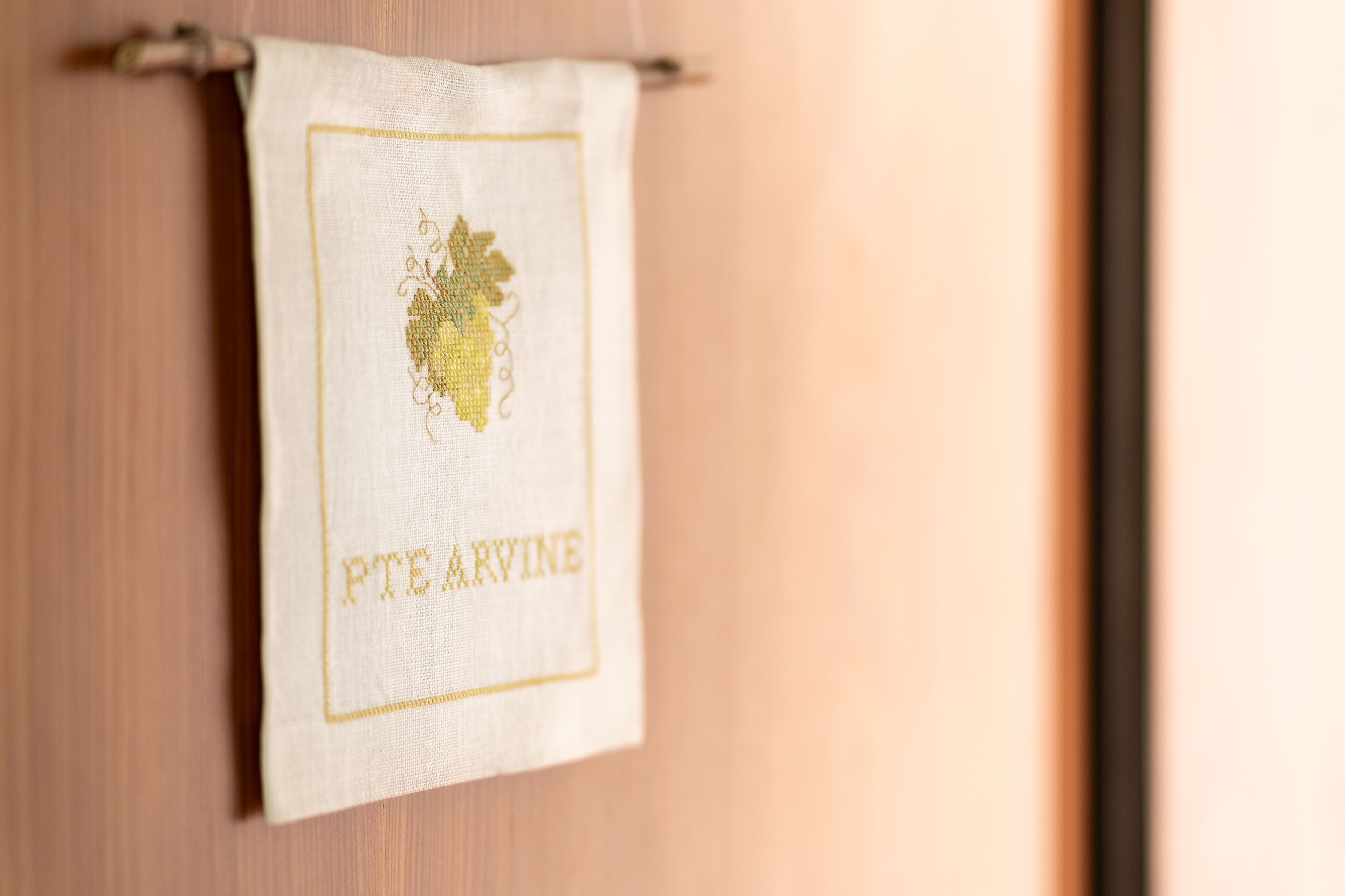 A white towel with a grapevine and the text "FTE ARVINE" hanging on a wooden door.
