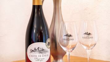 A bottle of wine, two wine glasses, and a vase with roses.
