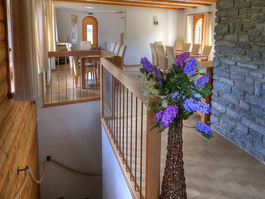 Una escalera con barandillas de madera que lleva a un comedor con mesa y sillas.