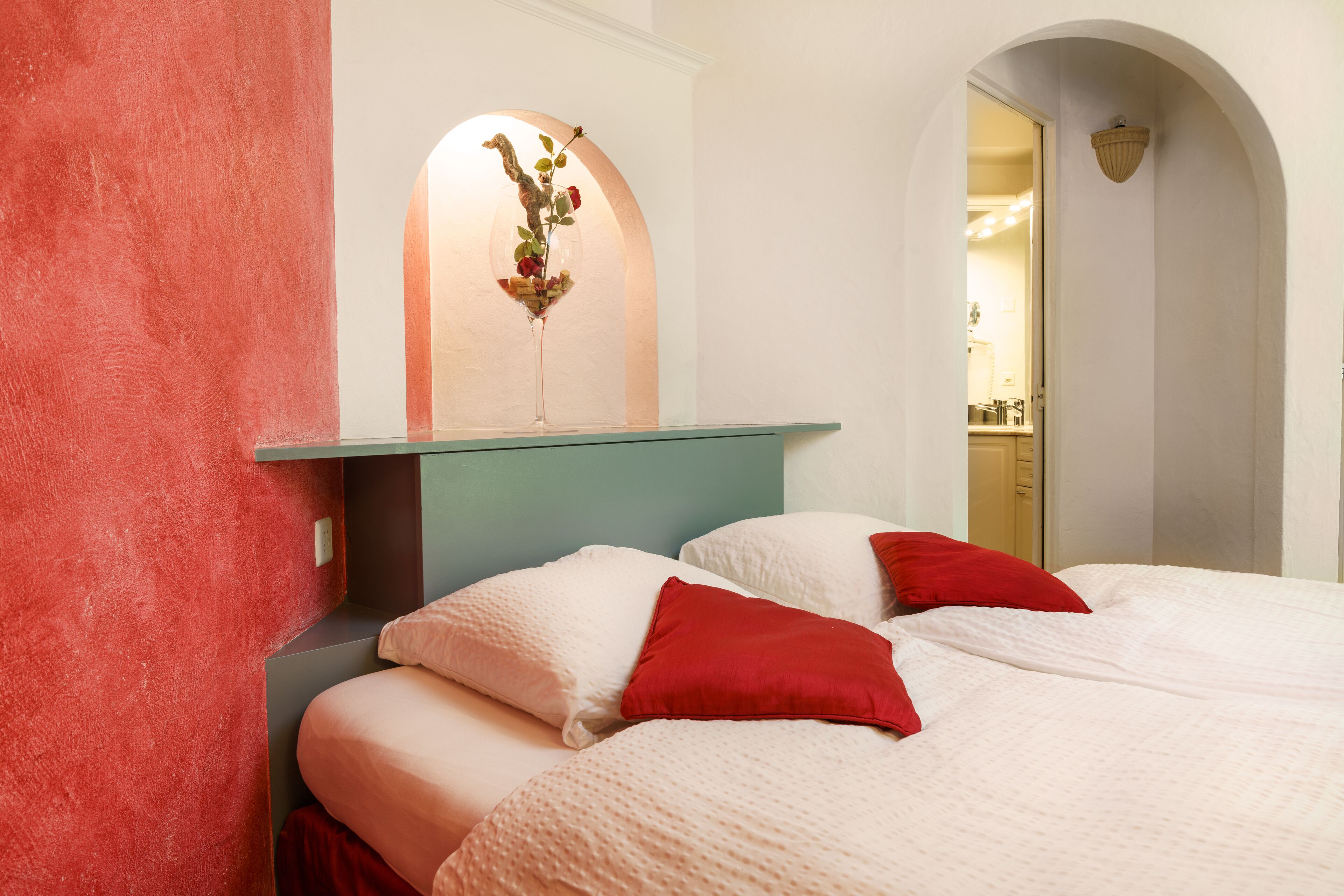 Un dormitorio con cama, almohadas, un estante en la pared y un objeto decorativo.