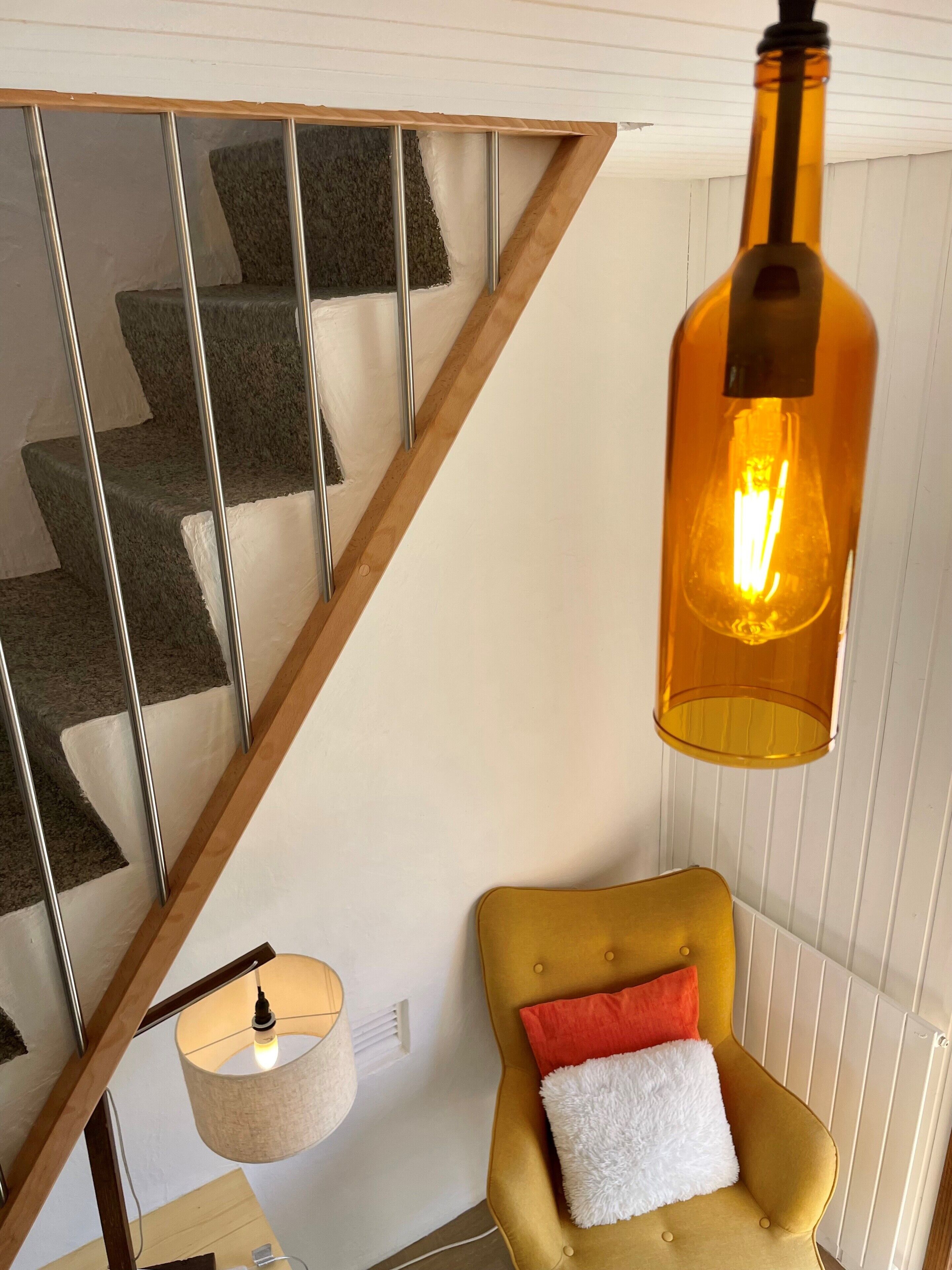 Un escalier avec des rampes en métal et un fauteuil jaune agrémenté d’un coussin blanc et rouge.