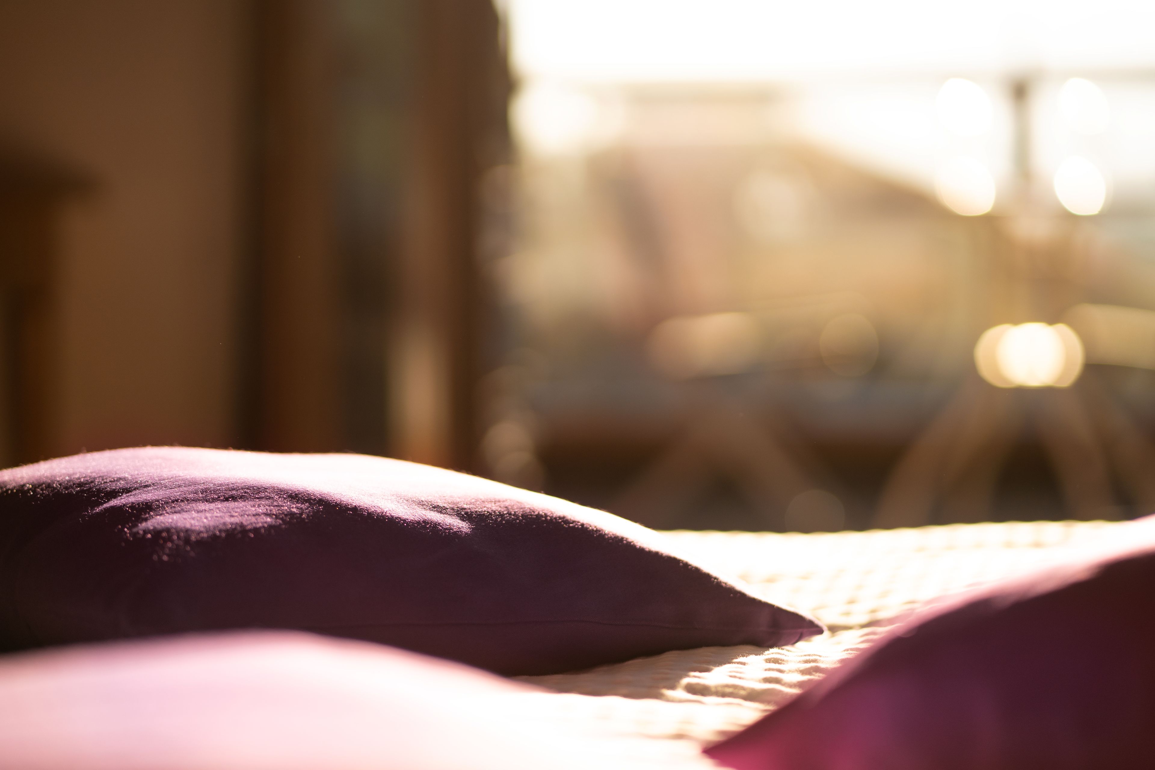 Un primo piano di un letto con un cuscino viola e una coperta bianca.