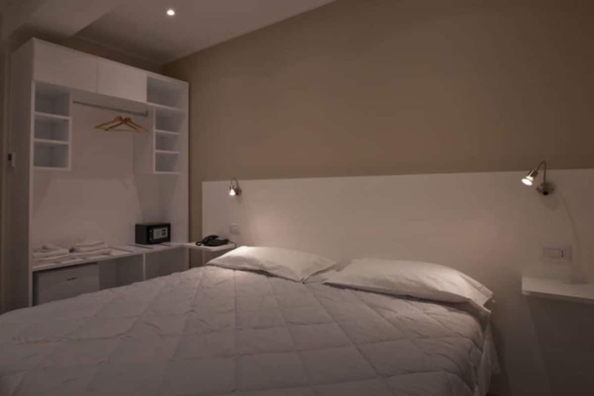 Un dormitorio con cama, mesita de noche y armario con perchero.