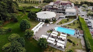 Vue aérienne d’une propriété dotée d’une piscine, d’un espace salon extérieur et d’un grand bâtiment circulaire.