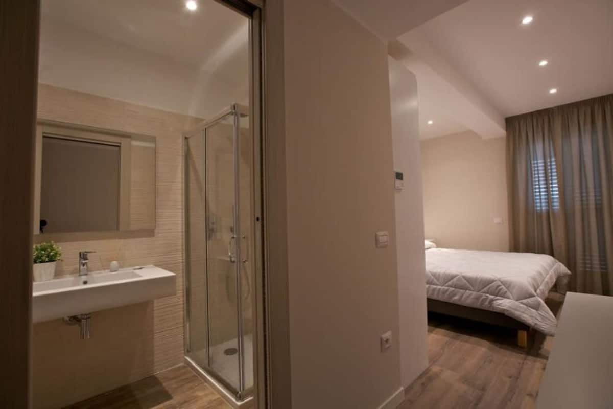 Un baño moderno con cabina de ducha de vidrio, un lavabo y un espejo.