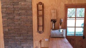 Una mesa de madera con sillas, una pared de piedra y una ventana con vistas a la vegetación.