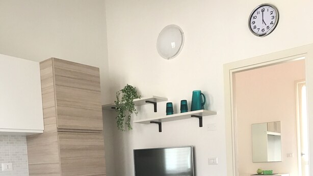 Una cocina moderna con comedor, televisor y un reloj en la pared.