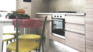 Una cocina con estufa, horno y comedor con sillas y mesa.