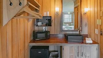 Un bagno compatto con lavandino, forno a microonde e piccolo frigorifero.