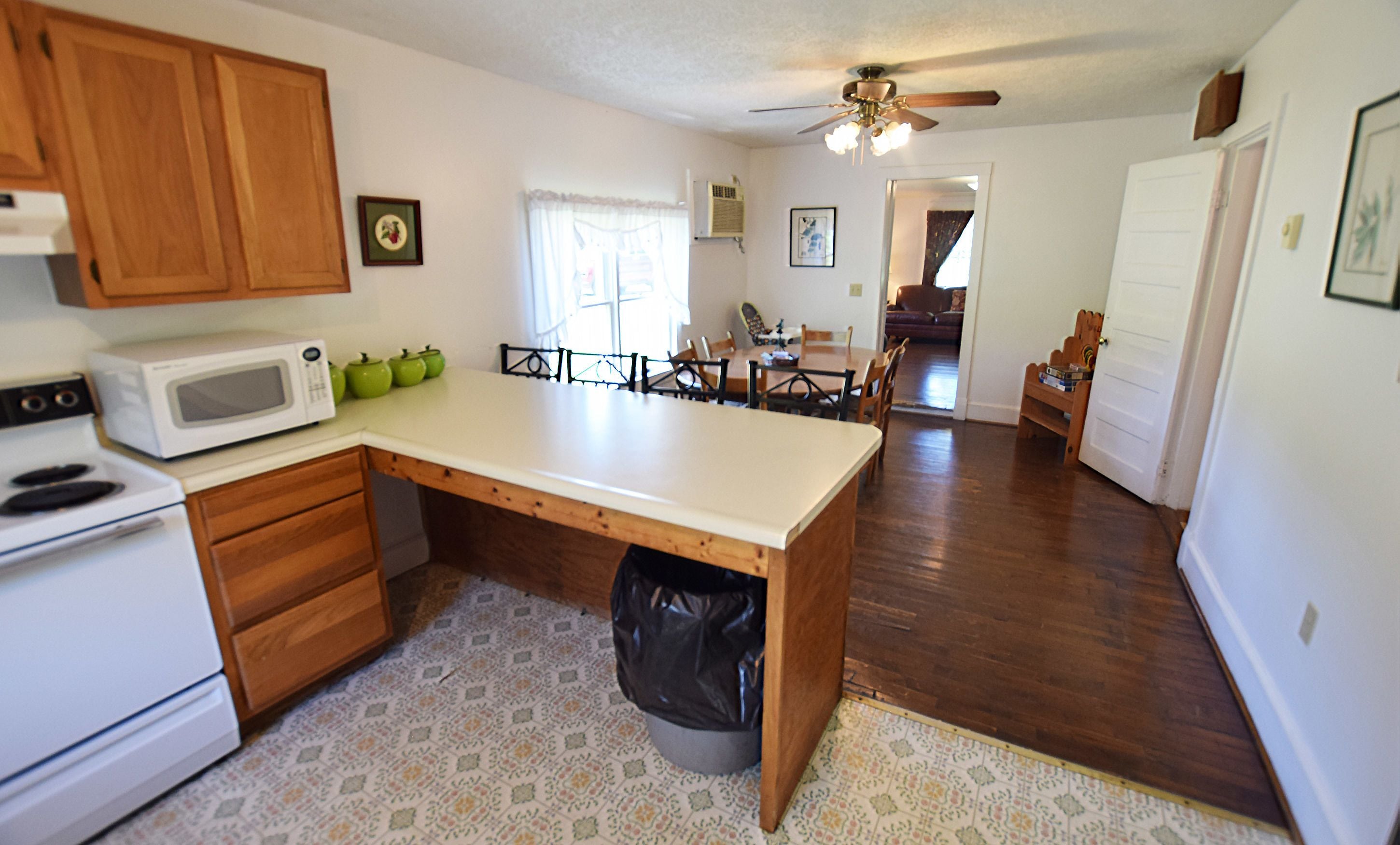 Una cocina con armarios de madera, un microondas y un comedor con mesa y sillas.