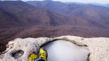 Una persona sentada sobre una roca con vistas a un paisaje montañoso.