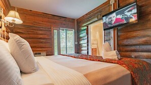A wooden cabin room with a bed, a television, and a window. - Graves Mountain Farm & Lodges (Syria)