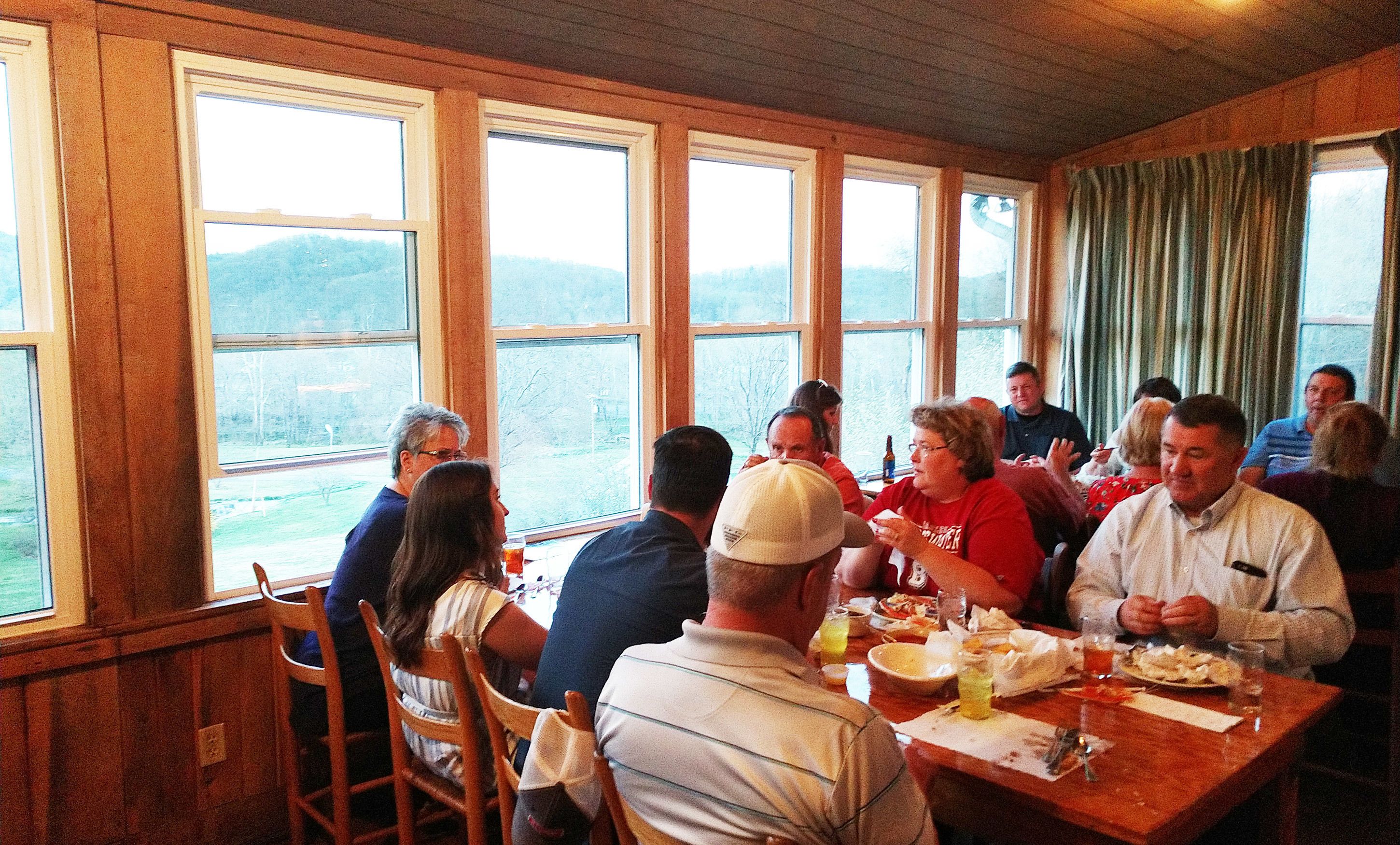 A group of people dining at a table with large windows overlooking a scenic landscape.