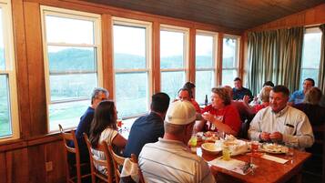 A group of people dining at a table with large windows overlooking a scenic landscape.