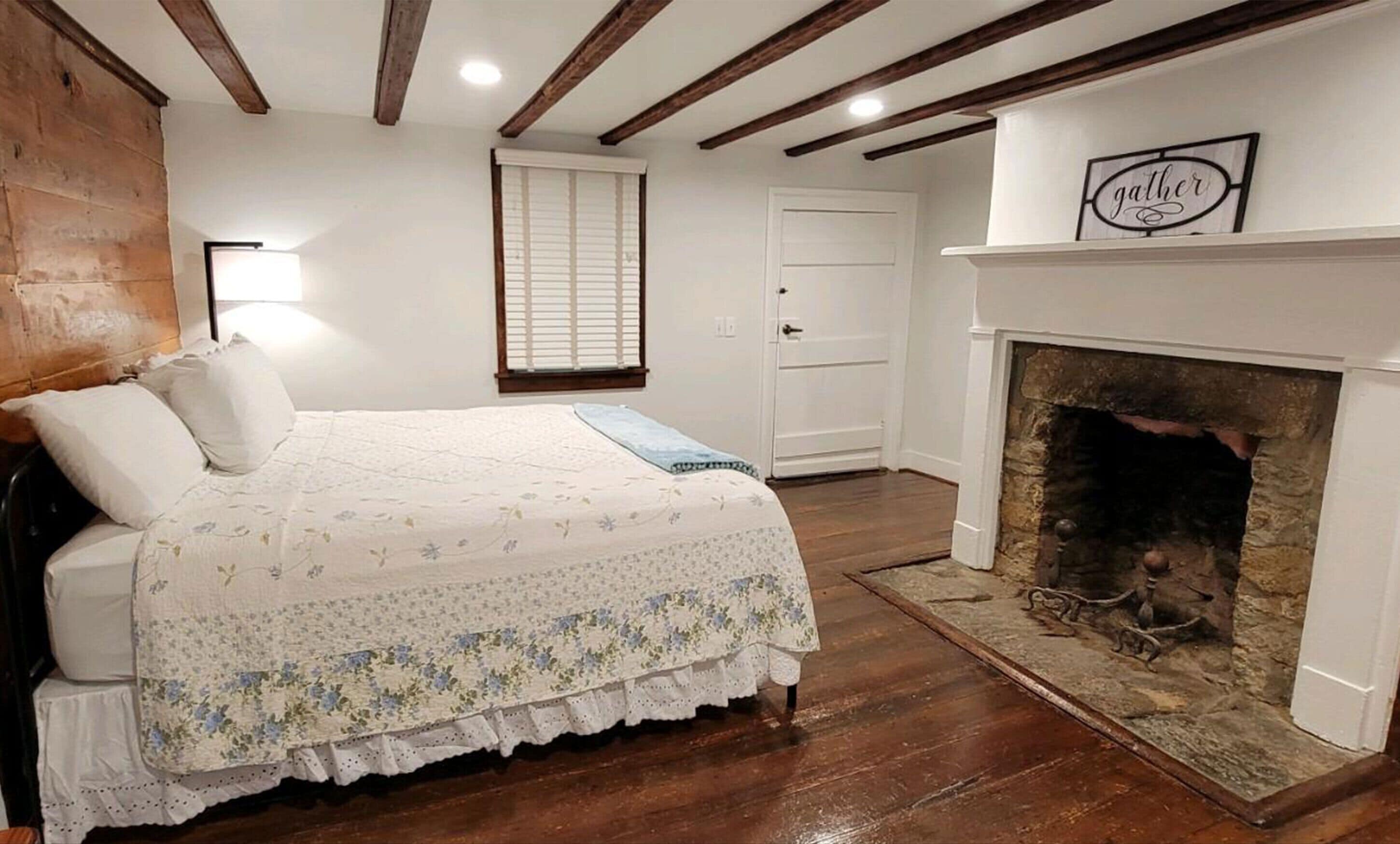 A bedroom with a bed, a fireplace, and a door.