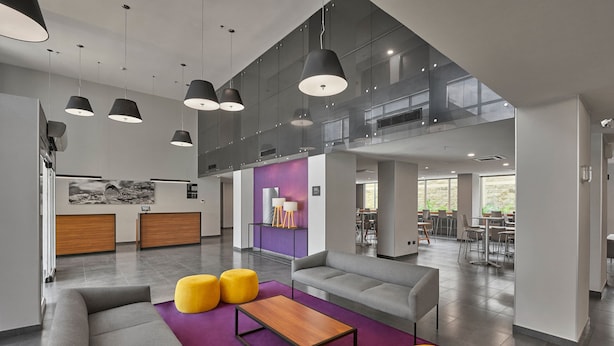 A modern lobby with a grey sofa, yellow ottomans, a wooden coffee table, and pendant lighting. - City Express by Marriott Tapachula (Tapachula)