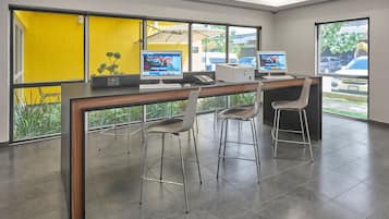 A modern office with two computers, a desk, and two bar stools.