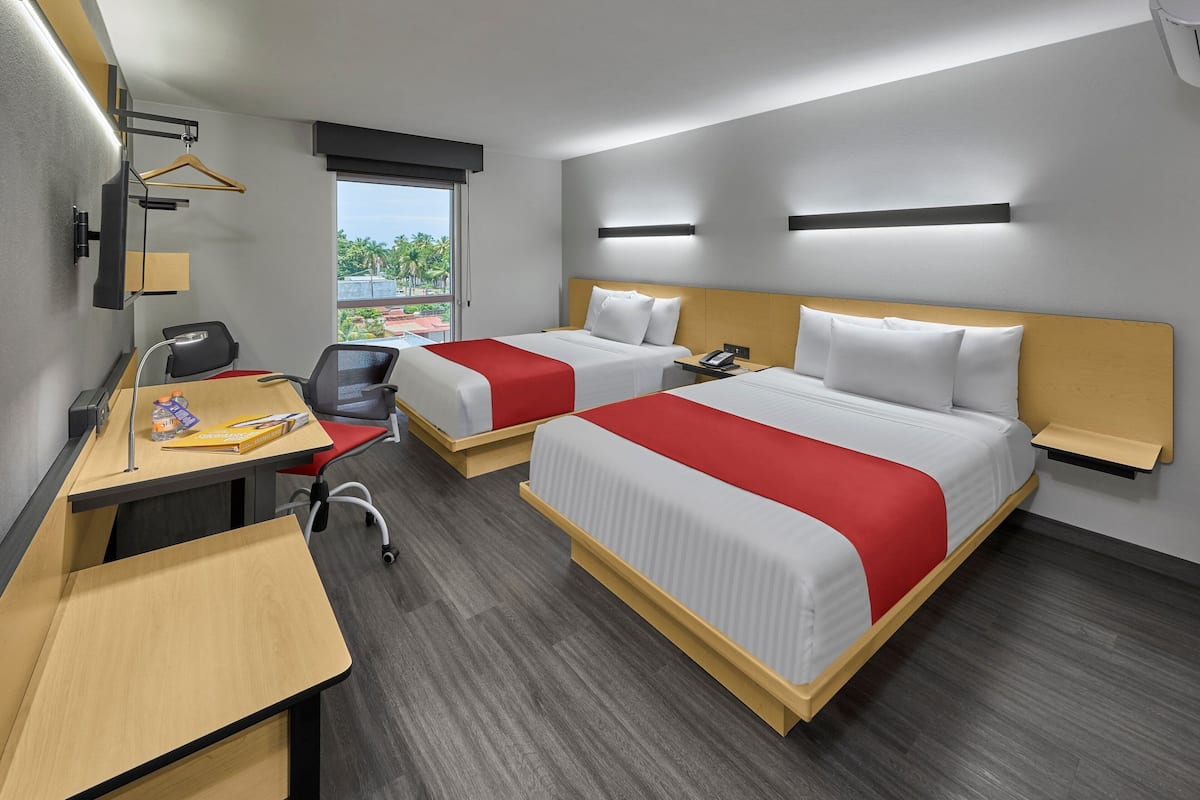 A hotel room with two beds, a desk, and a chair.