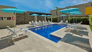 A swimming pool with lounge chairs and umbrellas, surrounded by a tiled patio. - City Express by Marriott Tapachula (Tapachula)