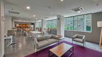Un área de estar moderna y bien iluminada con un sofá, sillones y una mesa de centro.