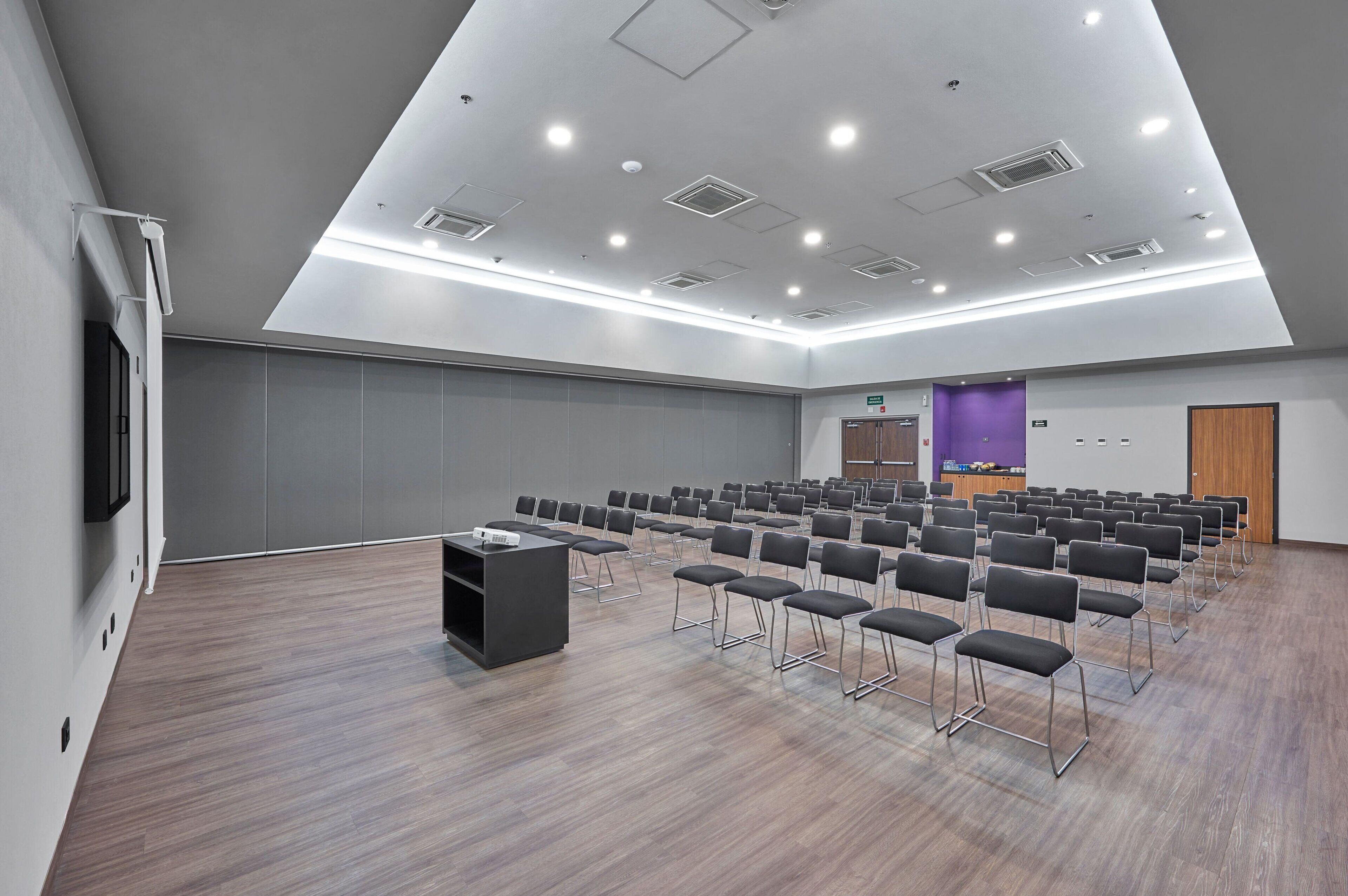 A conference room with rows of chairs, a projector, and a stage area.