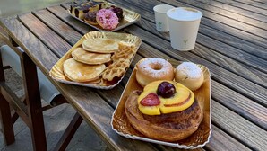 A wooden table with a variety of breakfast items including pancakes, waffles, donuts, and a fruit tart. - Hotel Deanna Golf (Cervia)