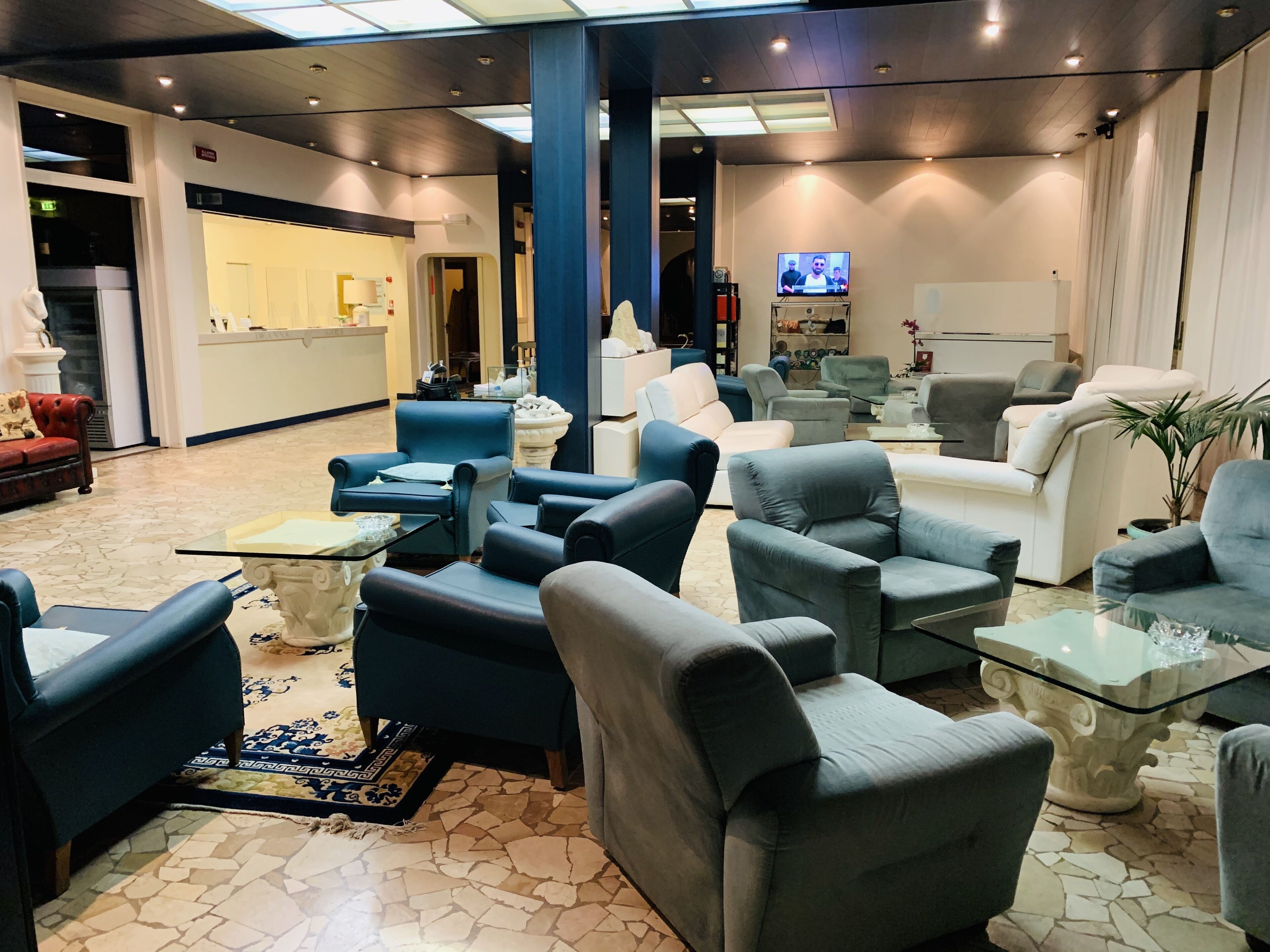 A lobby with multiple seating areas, a reception desk, and a television screen.