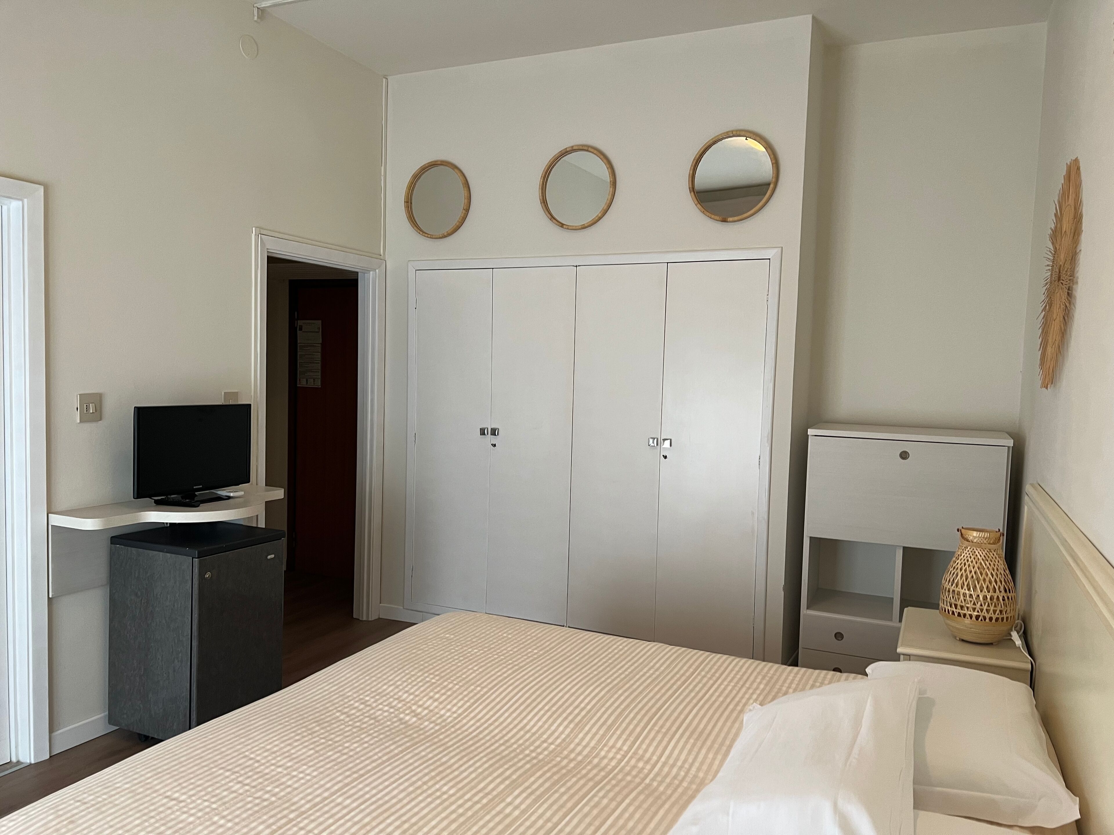 Una camera da letto con un letto, una televisione, un armadio e un comodino con una lampada.