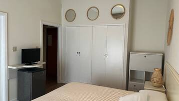 Una camera da letto con un letto, una televisione, un armadio e un comodino con una lampada.