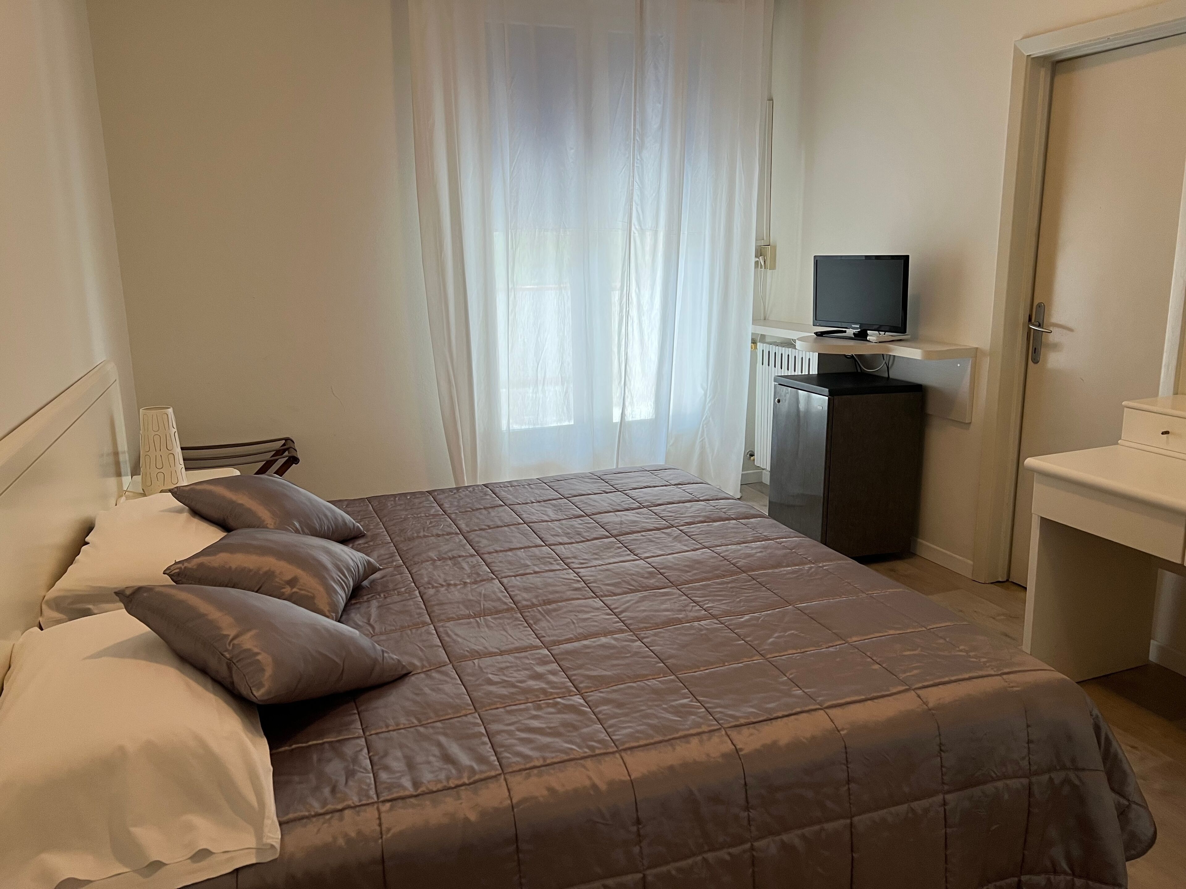 Une chambre d’hôtel équipée d’un lit, d’une télévision, d’un bureau et d’un radiateur.