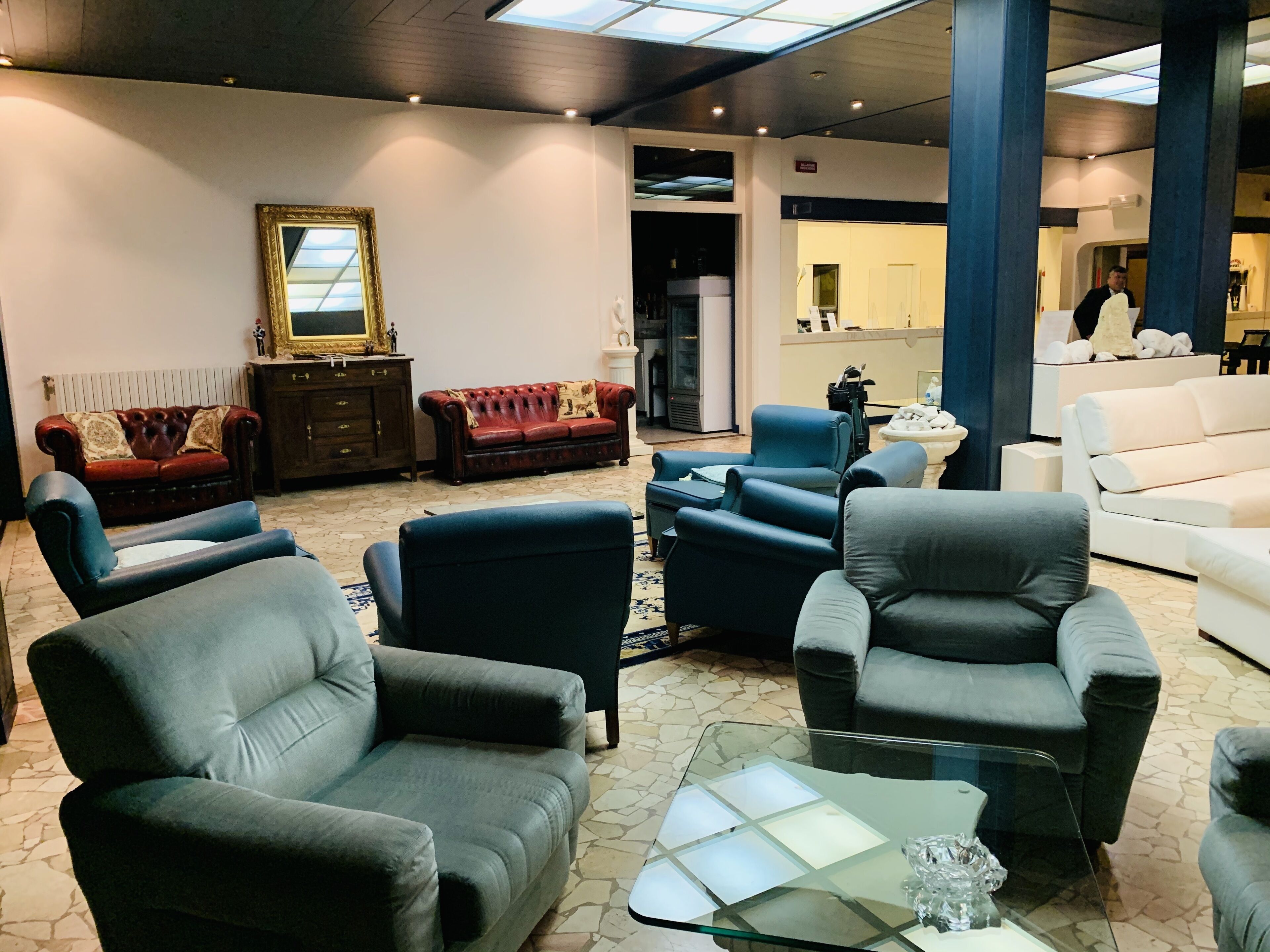 A modern lounge area with leather sofas, a glass coffee table, and a large mirror.